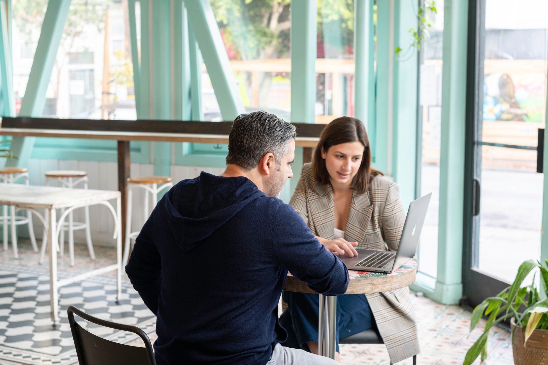 Duas pessoas conversando enquanto usam um computador em um café