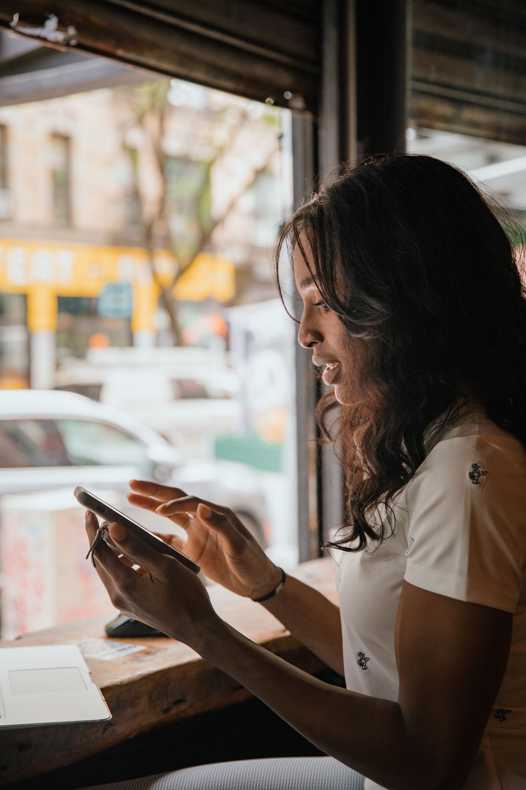 Mulher usando o celular à mesa de um café